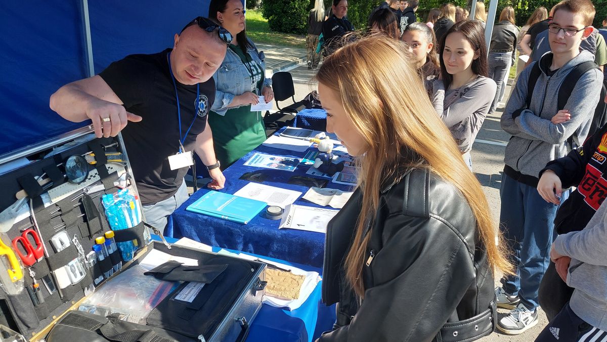 Policjant technik kryminalistyki prezentuje sprzęt wykorzystywany do zabezpieczenia śladów.
