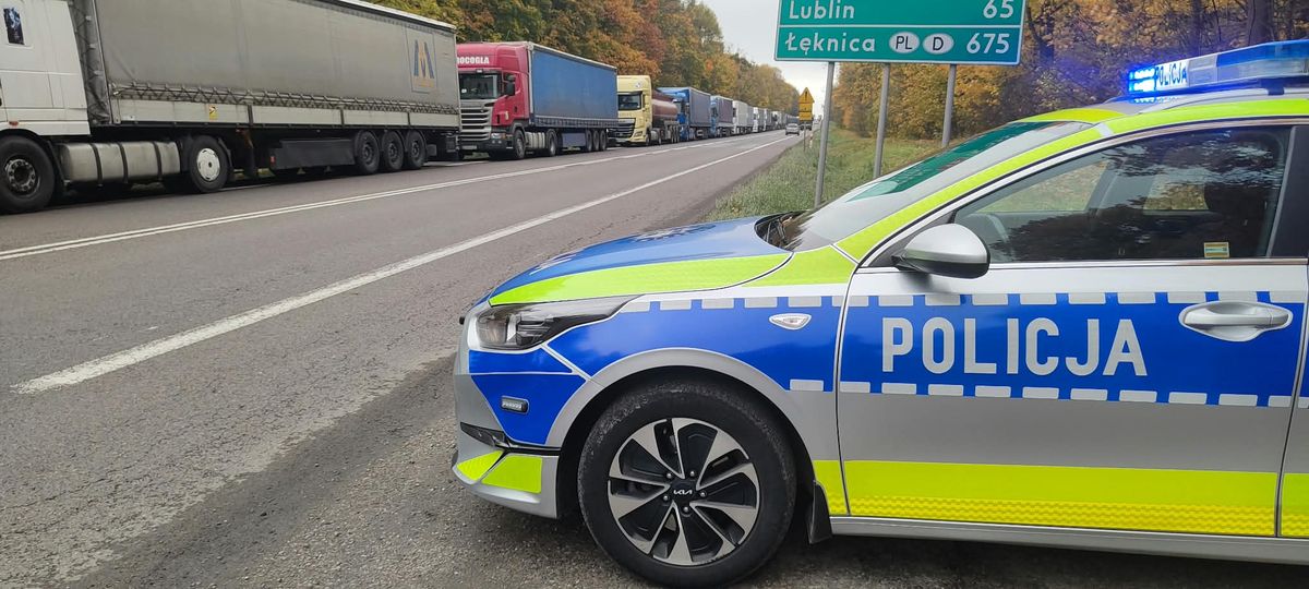 Radiowóz w poblizu kolejki tirów.