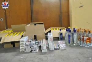 spirytus w pudełkach, papierosy oraz wódka stojące na szarym podłożu