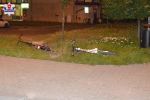 Dwa rowery leżące na trawniku obok chodnika.