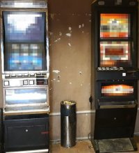 Dwa automaty do gier hazardowych stojące pod ścianą.