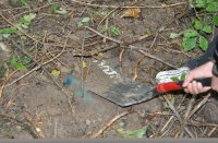 Wykopywanie szpadlem w lesie skradzionych elektronarzędzi