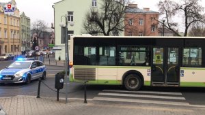 Stojący na przejściu dla pieszych autobus, za którym stoi radiowóz
