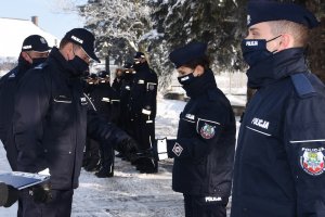 Komendant Miejski Policji w Chełmie wręcza nowym policjantom legitymacje służbowe. W tle kadra kierownicza komendy.