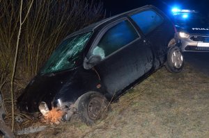 Uszkodzony przechylony samochód w rowie i stojący na poboczu radiowóz