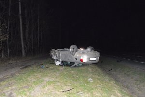 Uszkodzony samochód leżący na dachu na poboczu drogi