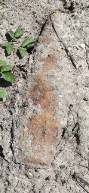 Leżący w ziemi skorodowany pocisk artyleryjski