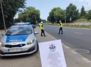 Policyjna kontrola drogowa i ulotka dekalogu kierowców w tle