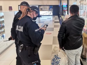 Policjanci legitymujący mężczyznę w centrum handlowym.