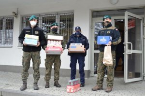 Policjantka i żołnierze przed budynkiem komendy.