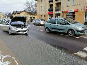 Dwa samochody stojące na jezdni, jeden z nich ma uszkodzony przód