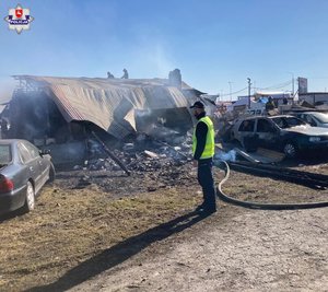 Policjant przed uszkodzonym przez wybuch gazu budynkiem.