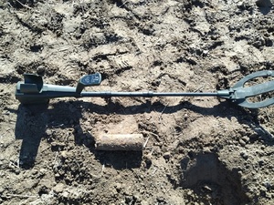 Skorodowany pocisk artyleryjski i przyrząd saperski na ziemi