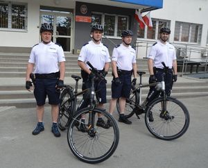 Policjanci z rowerami przed budynkiem komendy