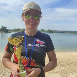 Policjantka w stroju sportowym z pucharem i medalem.