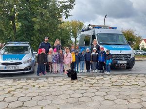 Dzieci przy radiowozach i policjant z psem słuzbowym