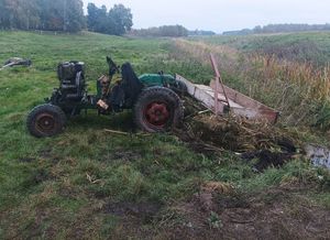 Ciągnik i wóz na brzegu rzeki na trawie.