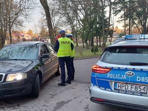 Policjantki prowadza kontrolę pojazdu, obok stoi radiowóz.