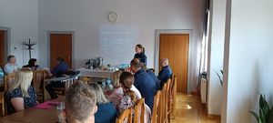 Uczestnicy debaty w sali i policjantka.