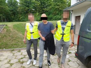 Policjanci prowadzą zatrzymanego mężczyznę