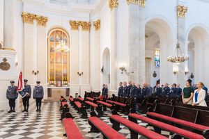 Poczet sztandarowy, policjanci i pracownicy podczas mszy świętej w kościele.