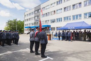 Poczet sztandarowy, policjanci i zaproszeni goście na placu przed budynkiem komendy.