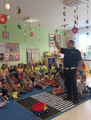 Policjant i dzieci w sali przedszkolnej.