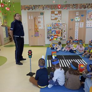 Policjant i dzieci przedszkolne w sali.