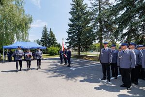 Policjanci niosą flagę do podniesienia.