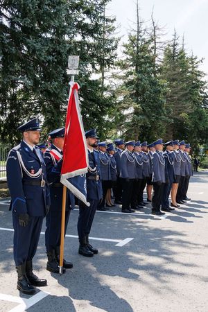 Poczet sztandarowy Komendy Miejskiej Policji w Chełmie w tle policjanci.