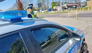 Policjanci przy radiowozie w pobliżu przejścia dla pieszych.