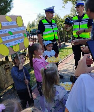 Policjanci i dzieci wręczające kierowcy cytrynę.