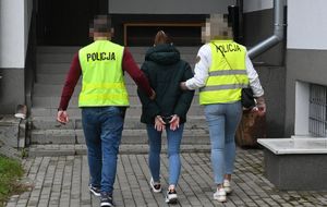 Policjanci prowadzą zatrzymana kobietę