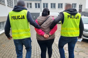 Policjanci prowadzą zatrzymaną kobietę