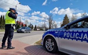 Policjant z miernikiem prędkości przy drodze.