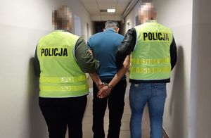 Policjanci prowadzą zatrzymanego mężczyznę.