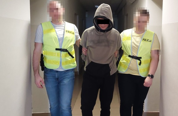 Policjanci prowadzą zatrzymanego mężczyznę.