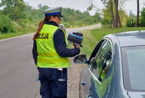 Policjantka prowadzi kontrolę pojazdu.