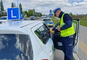 Policjant prowadzi kontrolę drogową samochodu do nauki jazdy.