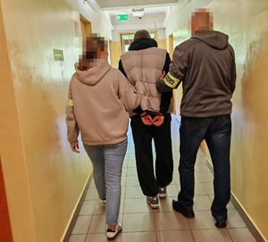 Policjanci prowadzą zatrzymanego mężczyznę.