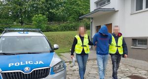 Policjanci prowadzą zatrzymanego mężczyznę.