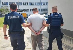 Policjanci prowadzą zatrzymanego mężczyznę.