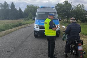 Policjant prowadzi kontrolę motocyklisty na drodze.