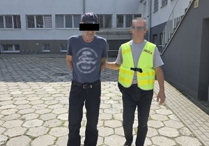 Policjant prowadzi zatrzymanego mężczyznę.