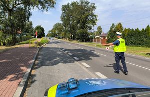 Policjant zatrzymuje samochód do kontroli drogowej.