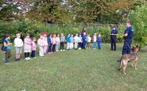 Dzieci na spotkaniu z policjantem psa służbowego i jego czworonożnym podopiecznym.