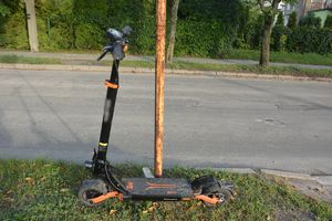 Hulajnoga elektryczna stojąca w pobliżu jezdni.