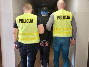 Policjanci prowadzą zatrzymaną kobietę