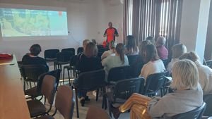 Ratownik medyczny prowadzi teoretyczne szkolenie pracowników komendy na sali konferencyjnej w budynku komendy.