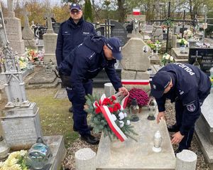 Policjanci składają wieniec i zapalają znicz na pomniku poległego policjanta